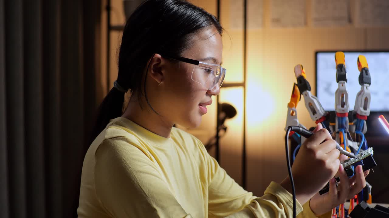 Close Up Of Teen Asian Girl Holding And Fixing The Circuit Board While Repairing A Cyborg Hand At Home