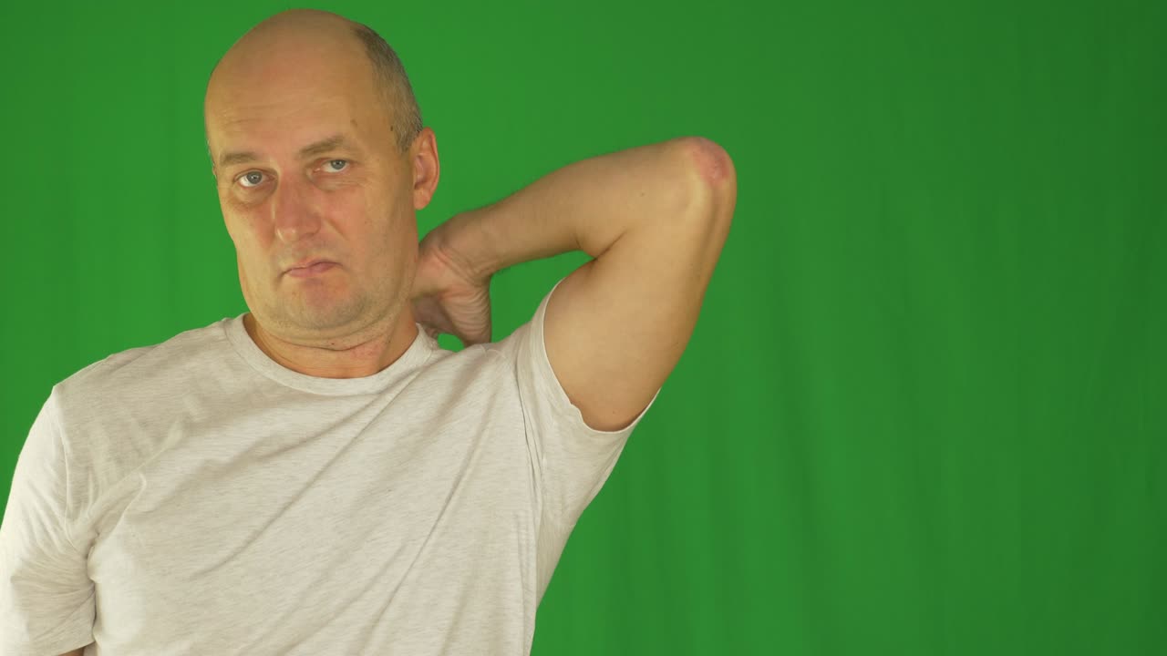 남자가 왼손으로 목과 어깨를 문지르고 있다. 가까운 전면 뷰. 잠겨진.