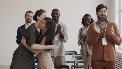 diverse colleagues clapping hands and hugging