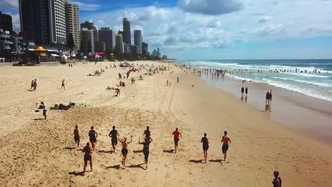 aerial tracking view of people jogging along the beach