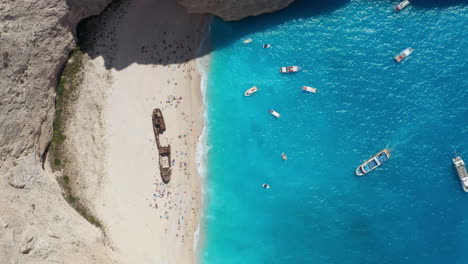 Berühmter-Navagio-strand-Mit-Schiffswrack---Boote,-Die-Auf-Türkisfarbenem-Wasser-Der-Küste-Von-Zakynthos-In-Griechenland-Schwimmen