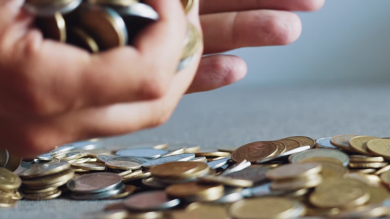 Man's hands holding lots of coins. Slow motion.