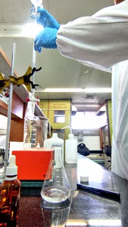 chemist wearing gloves handling lab equipment