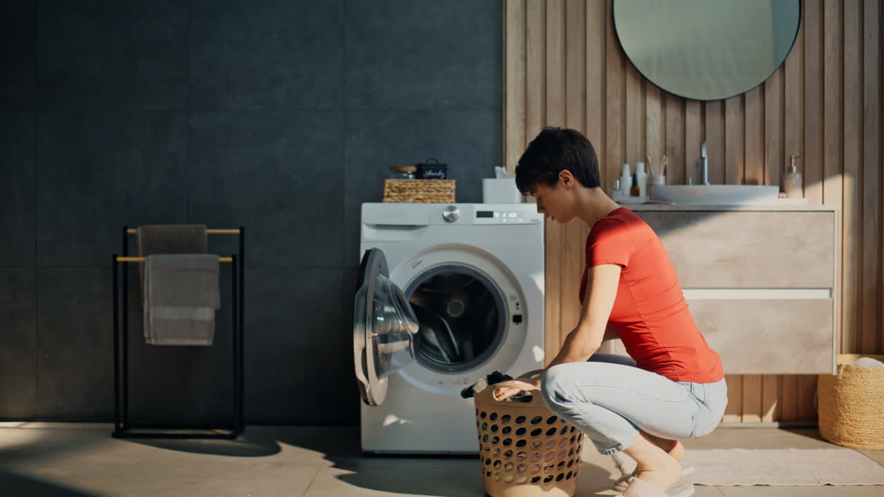 Closeup housewife entering bathroom making laundry. Lady loading washing machine