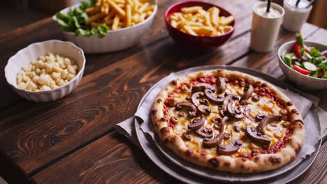 pizza with fries and salad on a wooden table