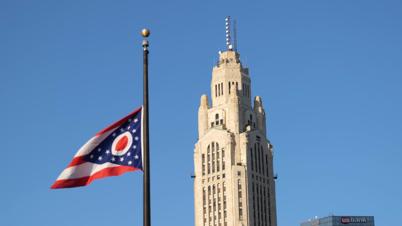 Leveque Tower in Columbus Ohio with the Ohio flag flying in slow motion in the foreground