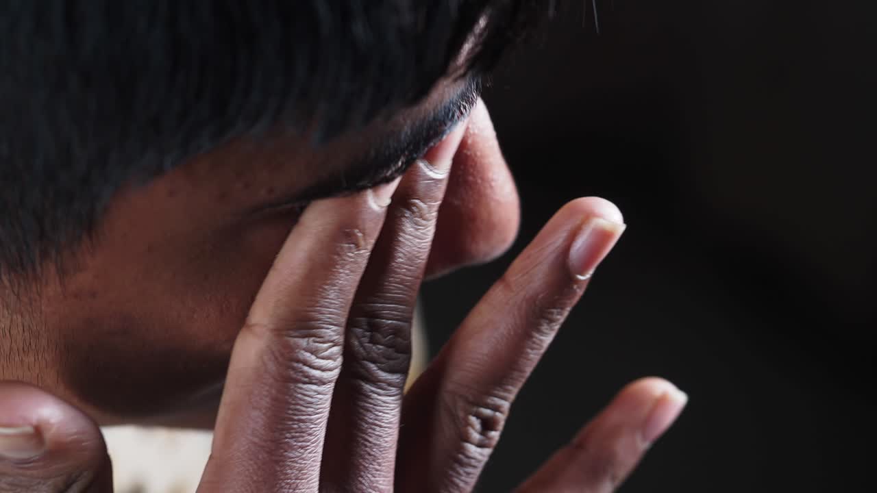 Close-up of a boy with his hand on his eye