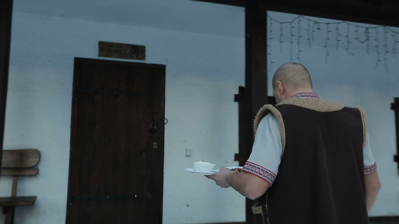 Waiter bears dishes. Back view of male waiter outside restaurant