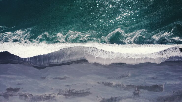 Drone shot from above of green sea and black sand beach in iceland 4k