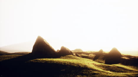 a beautiful sunset over a grassy field with rocks