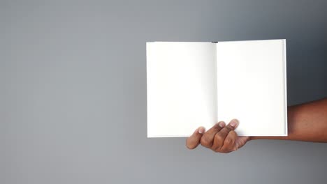 hand holding an open book with blank pages