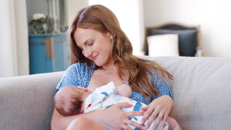 Slow-Motion-Shot-Of-Mother-Sitting-On-Sofa-At-Home-And-Breastfeeding-Baby