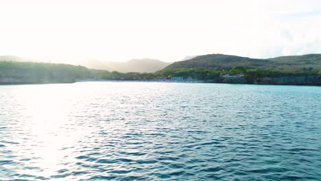 Aerial-trucking-pan-over-ocean-with-Grote-Knip-Curacao-beautiful-beach-in-distance-at-sunrise