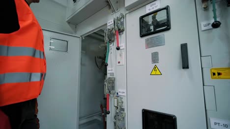 el ingeniero eléctrico que trabaja comprueba la tensión de corriente eléctrica y la sobrecarga en la parte delantera del gabinete del centro de carga o de la unidad de consumo para el mantenimiento en la sala principal del sistema de distribución de energía.