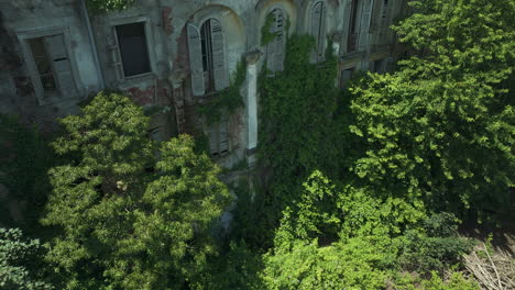abandoned school building covered in ivy and greenery, italy, aerial view
