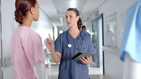 caucasian nurse talking with a nurse in a hospital corridor