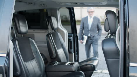 gente de negocios entrando en un auto con laptops y saludando