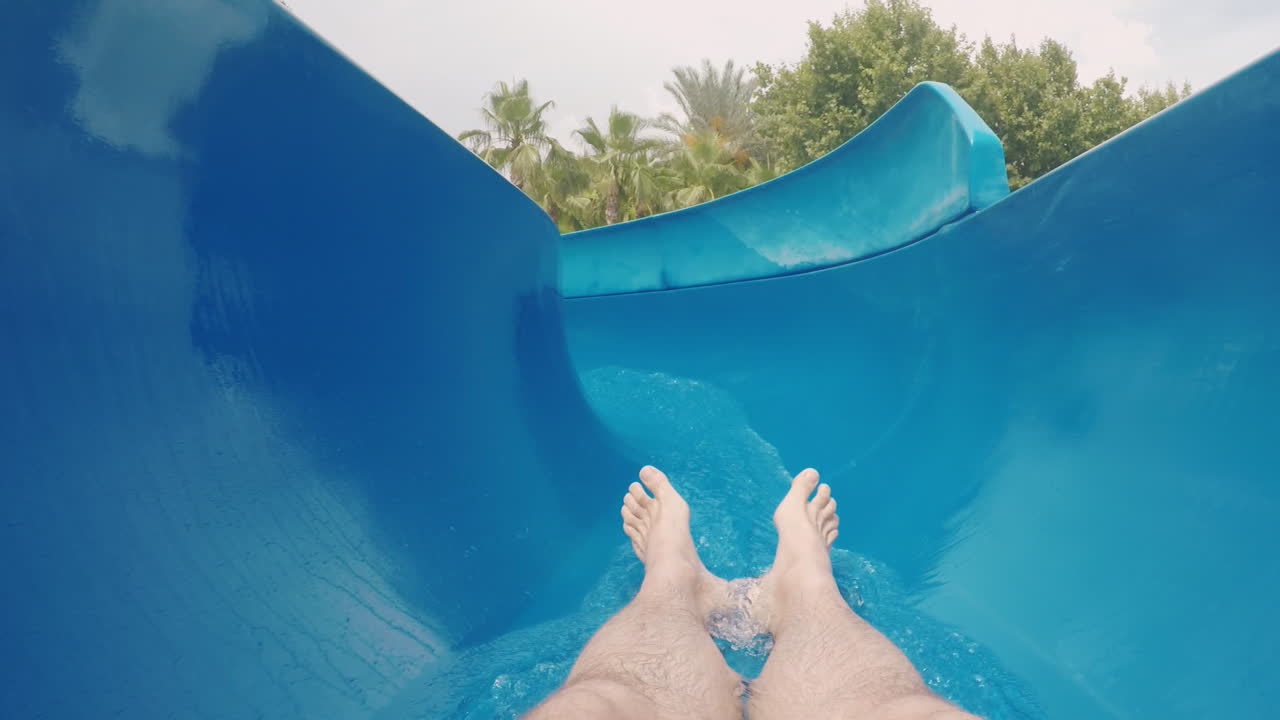 мужчина спускается с водной горки, глядя только на ноги