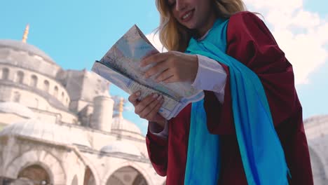 slow motion:attractive beautiful girl looks at map of istanbul with view of sultan ahmet mosque in istanbul,turkey