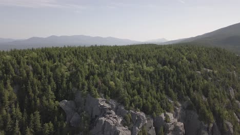 aerial drone shot flying away from mountain cliff and forest