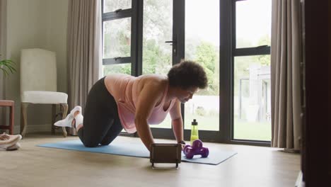 Video-of-midsection-of-plus-size-african-american-woman-exercising-with-online-lessons-at-home