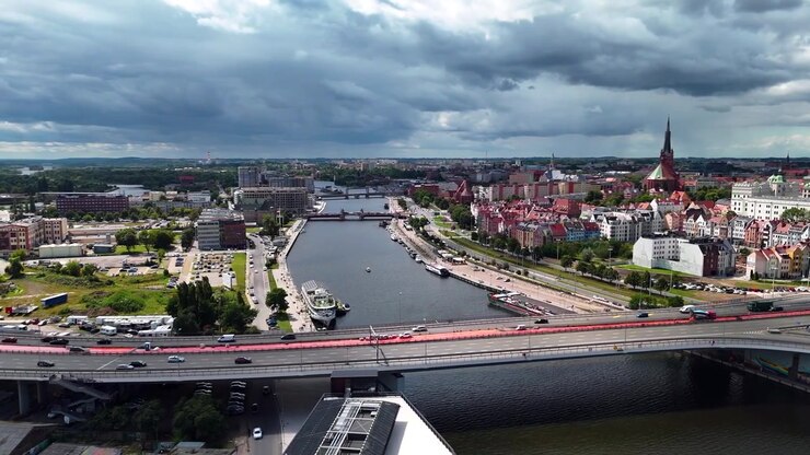 Una ripresa dall'alto che mostra il paesaggio urbano di Stettino, Polonia, con il fiume Odra, l'architettura storica e il traffico sul ponte Trasa Zamkowa sotto un cielo nuvoloso e drammatico