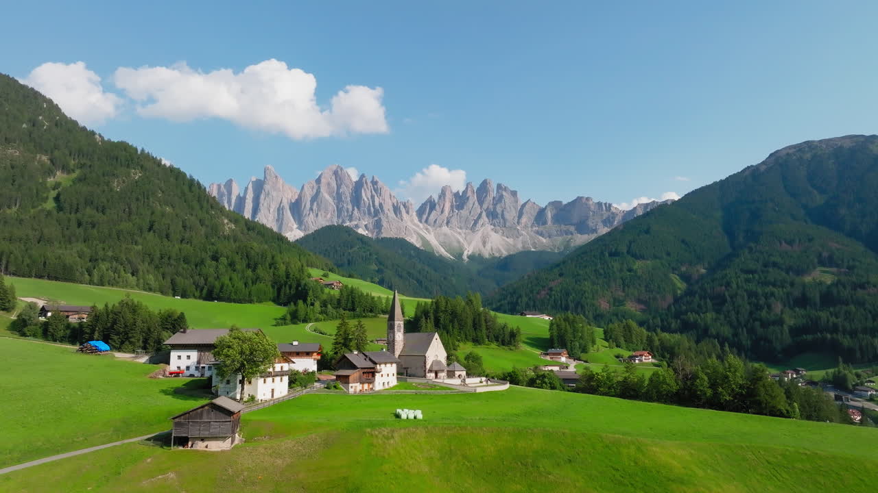 St Magdalena Church establishinged from hillside path with mountain range in clear daylight