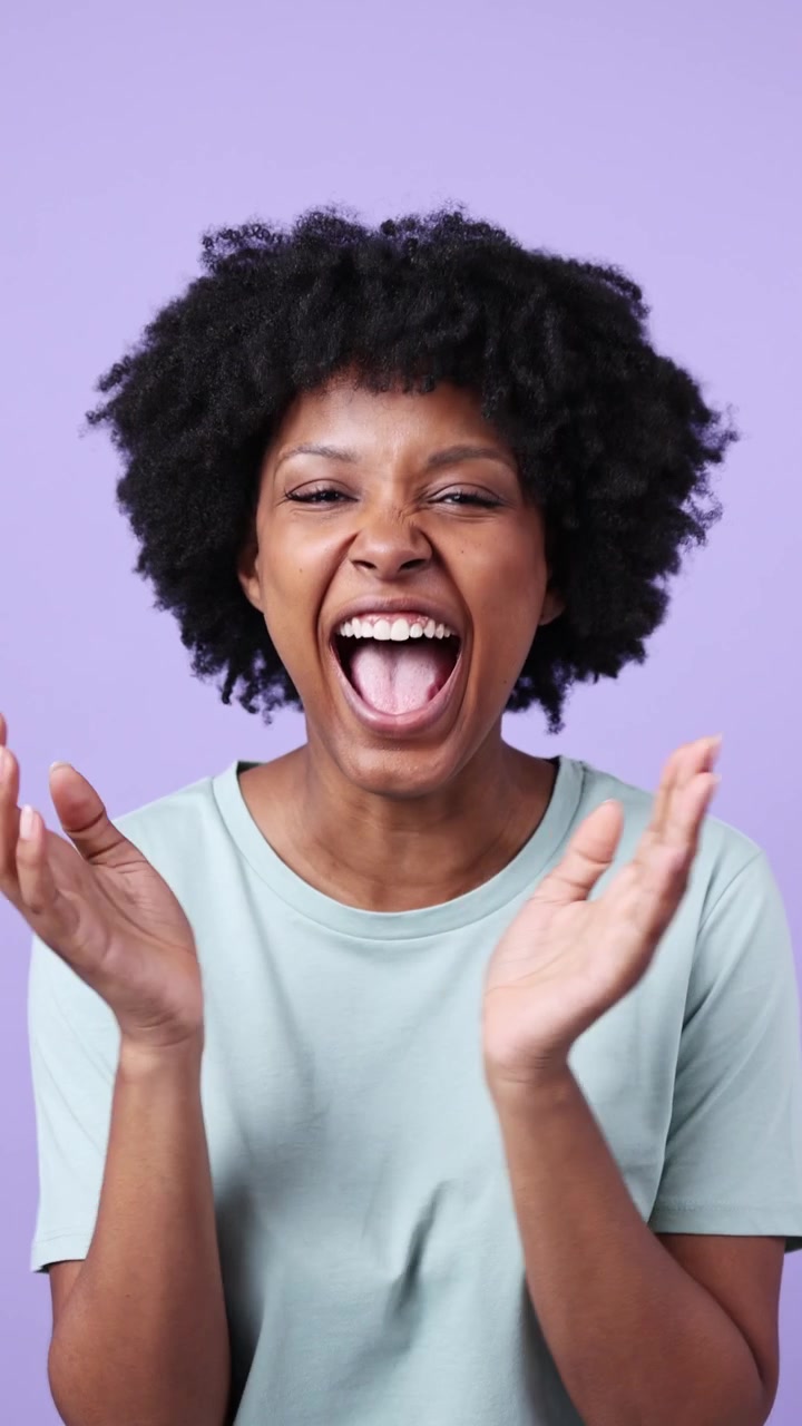 Femme afro-américaine heureuse riant et applaudissant sur fond violet
