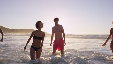 Eine-Vielfältige-Gruppe-Von-Freunden-Schwimmt-Bei-Sonnenuntergang-Im-Meer