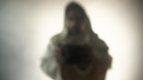 jesus christ in bright light, mist and fog, holding a clay jar of wine in slow motion, for a symbolic representation of the last supper, communion, sacraments, and the gospel.