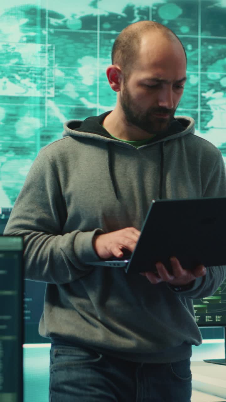 Mand, der står og skriver på bærbar computer i et højteknologisk kontrolrum