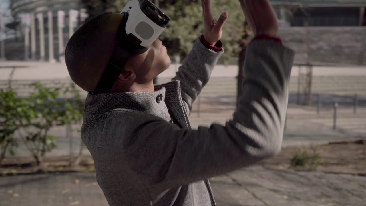 Jeune homme avec des lunettes de réalité virtuelle touchant quelque chose en extérieur