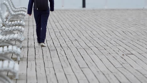 cropped portrait of a person walking on boardwalk with empty outdoor chairs