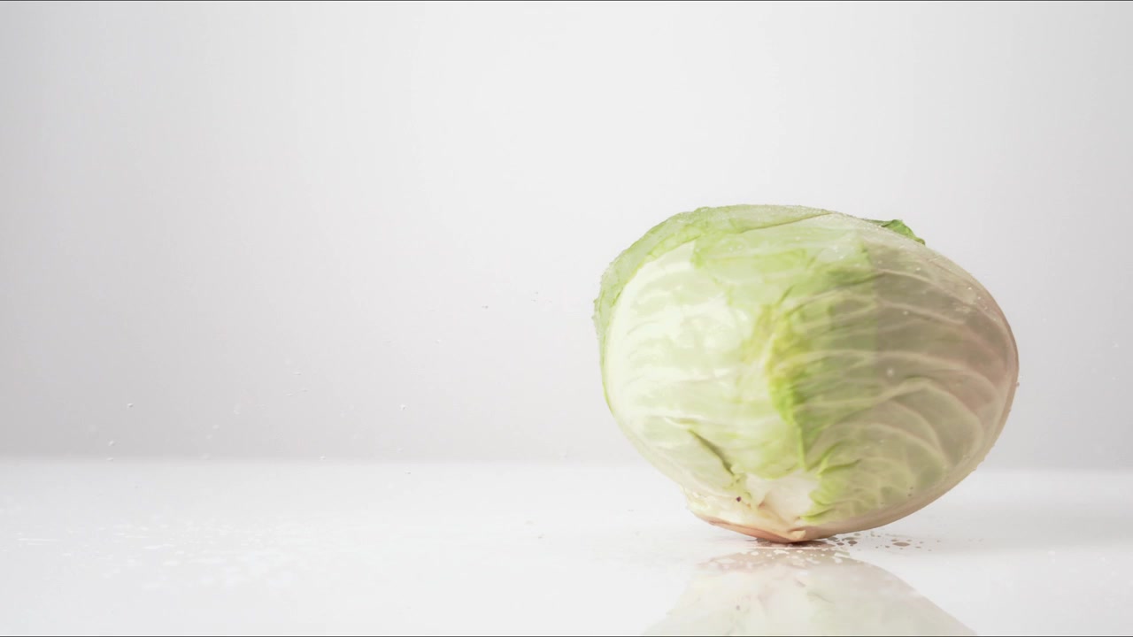 Fresh whole Green Cabbage spinning on a white backdrop in extreme slow motion 800fps high speed.