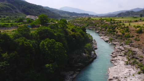 Stunning-drone-view-of-fresh-waters-of-Vjosa-river-amidst-beautiful-green-cliffs-and-mountains