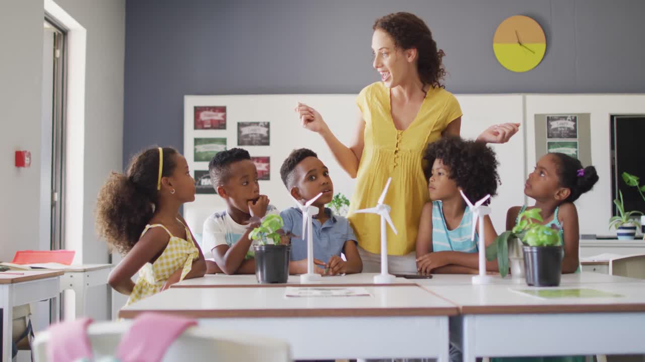 video de una feliz maestra caucásica y alumnos afroamericanos estudiando ecología en el aula