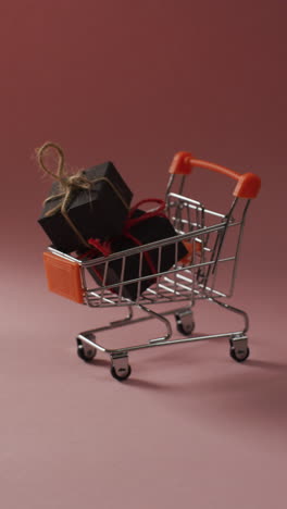 video vertical del carrito de compras con regalos en fondo rosa