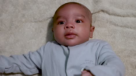 cute 2 month old baby boy wriggling on blanket looking up being animated