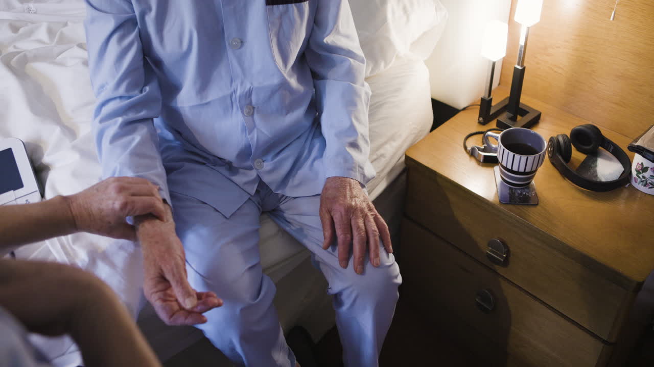 Elderly man being cared for by caregiver in bedroom