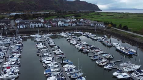 Scenic-luxurious-waterfront-harbour-apartment-village-yachts-and-sailboats-under-mountain-coastline-aerial-orbit-right-view