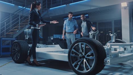 equipo internacional de ingenieros de diseño de automóviles hablando y diseñando automóvil eléctrico autónomo. el chasis de la plataforma del vehículo tiene ruedas, motores, batería. evolución de la eficiencia de la energía renovable limpia