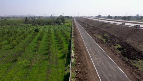 Carretera-Asfaltada-De-Un-Solo-Carril-Junto-A-Un-Huerto-Y-Nueva-Construcción-De-Carreteras-De-Autopista