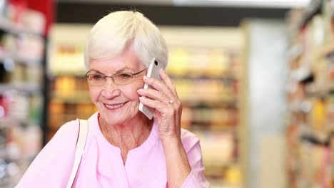 mujer mayor en el teléfono en el supermercado