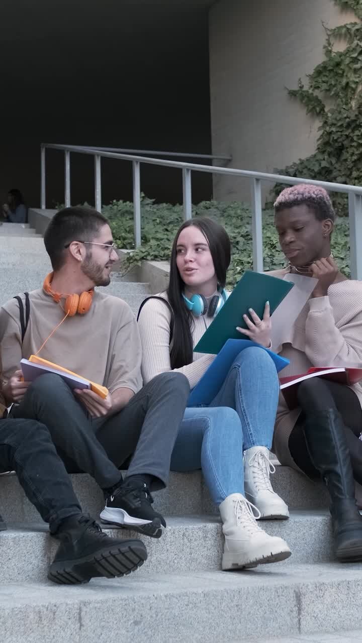 Gruppo di studenti che prende appunti seduto sulle scale dell'università.