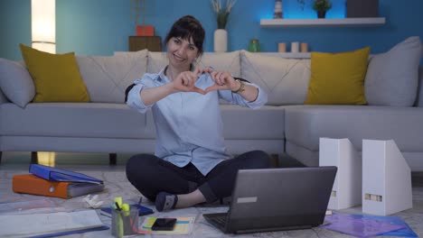 la mujer que trabaja en la oficina hace el símbolo del corazón mirando a la cámara.