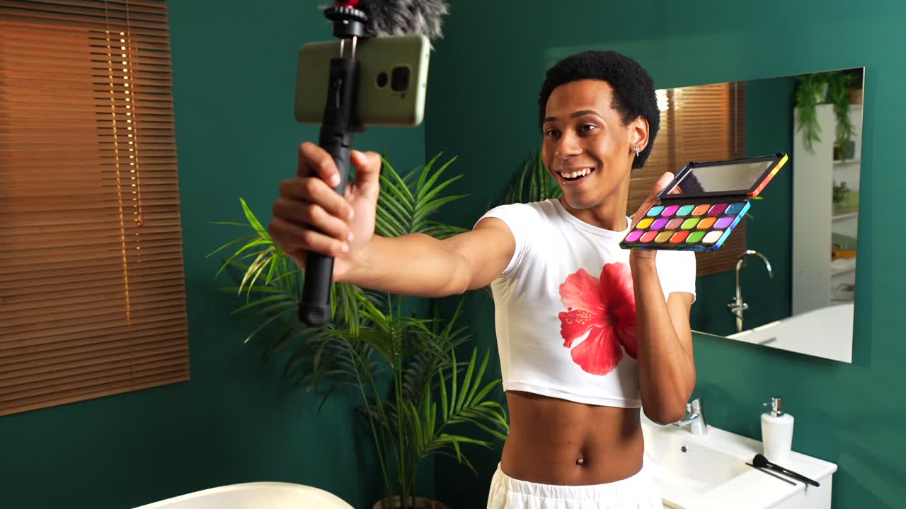 A person takes a selfie in their bathroom holding makeup