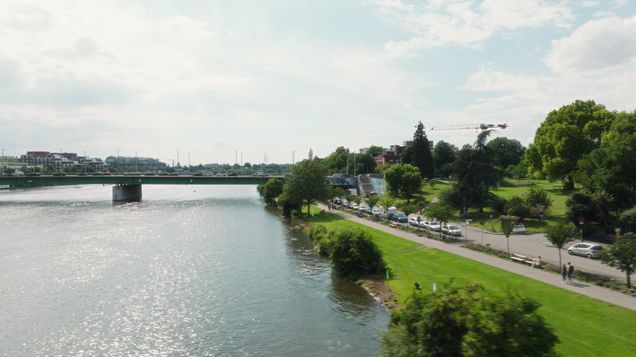 Drone flying diagonally above the Neckar toward Theodor-Heuss Bridge with traffic and riverside