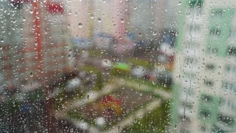 Raindrops on glass window. Water drops falling down on window pane in a rainy weather on city landscape.Wet drops on glass. Close-up.