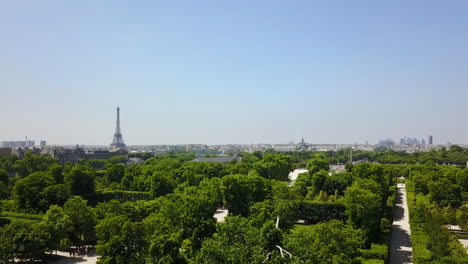 Rising-footage-of-trees-and-green-vegetation.-Revealing-cityscape-with-famous-Eiffel-Tower.-Paris,-France