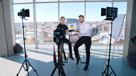 positive young people speaking about their project. entrepreneurs man and woman recording a video on professional camera in studio.